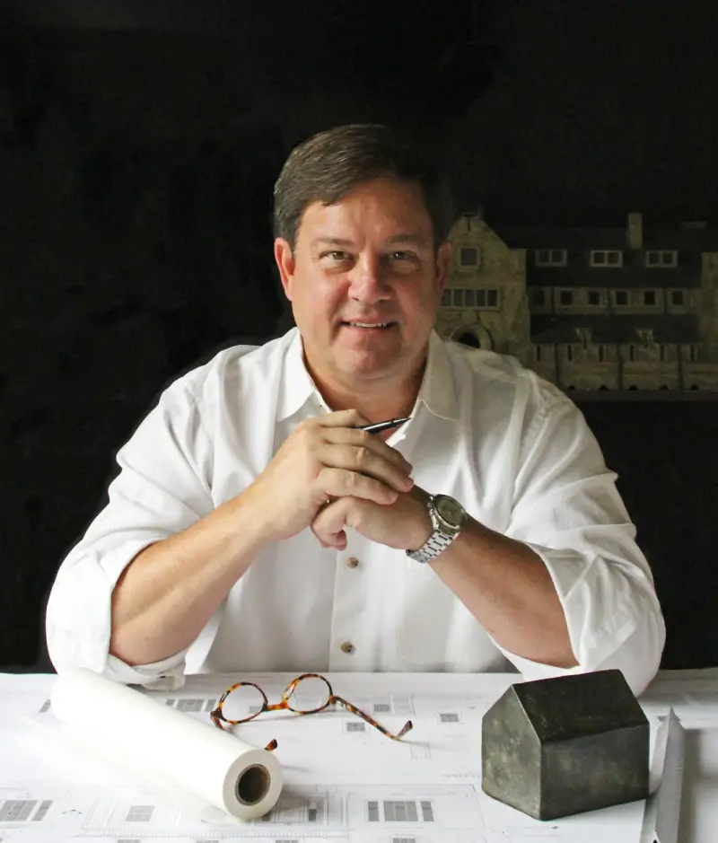 A man sitting at a table with his hands clasped.