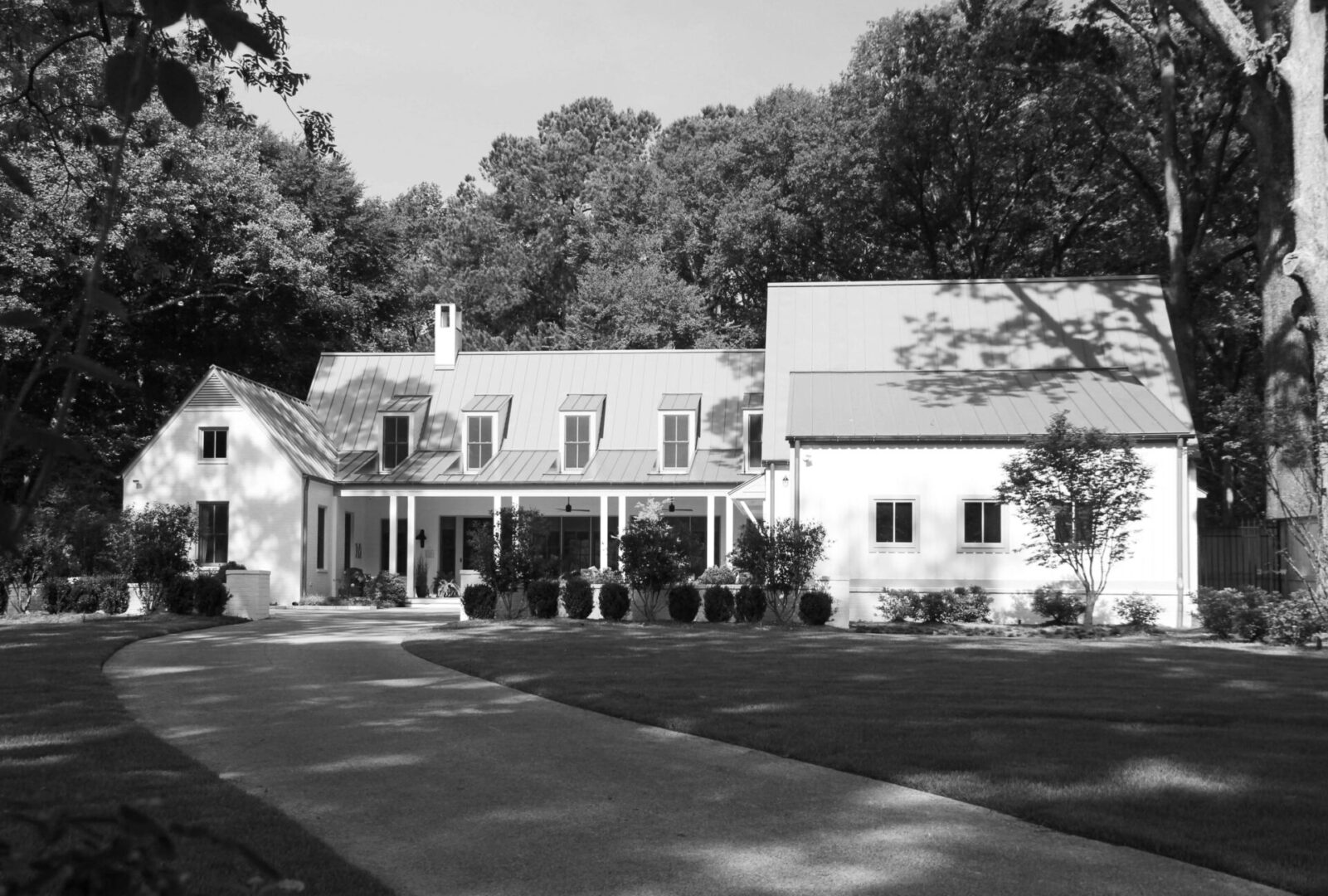 A black and white photo of a house with trees in the background.