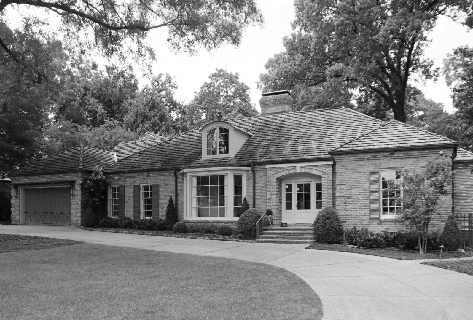 A black and white photo of a house with trees in the background.