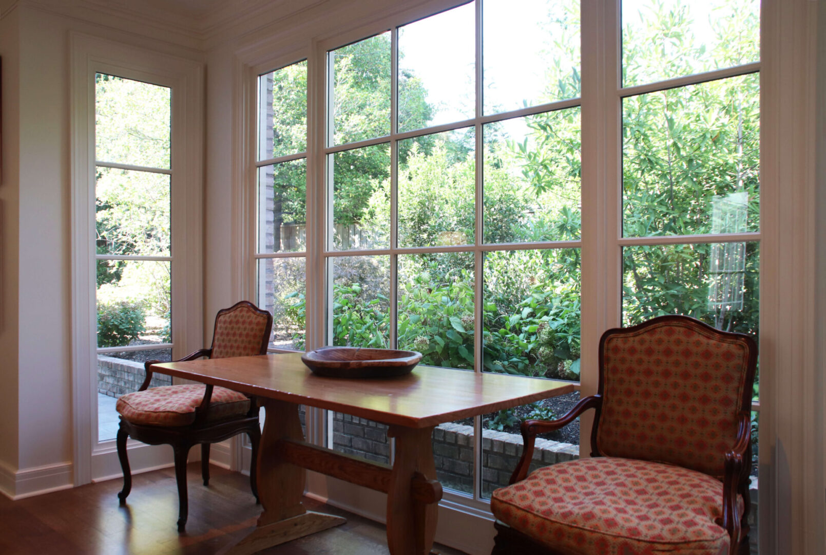 A dining room table with two chairs and a bowl on the table.