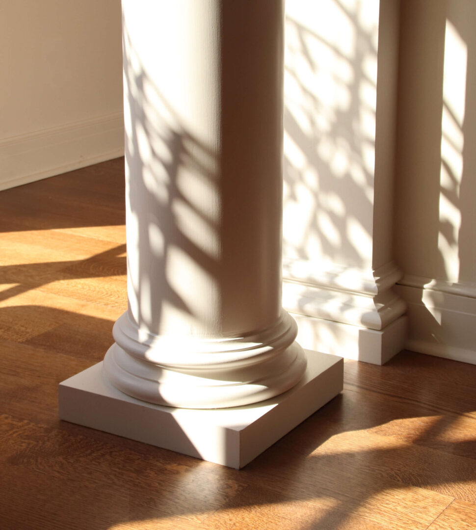 A white pillar with shadows on the ground.