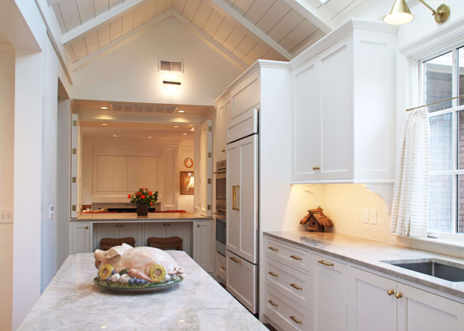 A kitchen with white cabinets and marble counter tops.