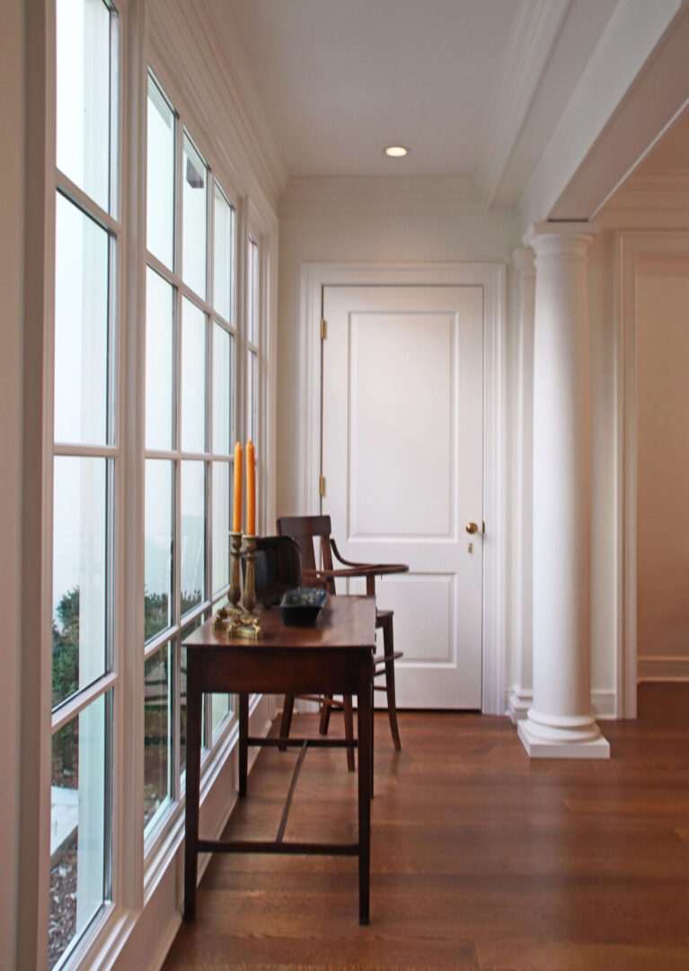 A hallway with a table and chairs, a door and windows.