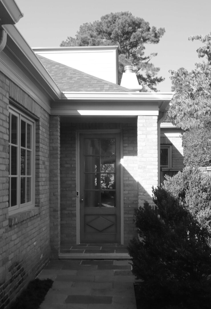 A black and white photo of a house with a door.