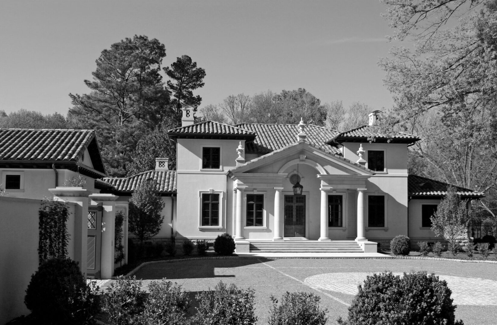 A large white house with a courtyard and trees.