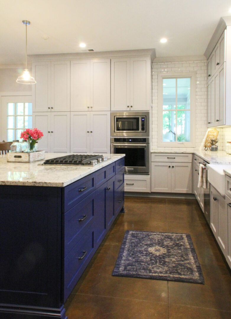 A kitchen with white cabinets and blue island.