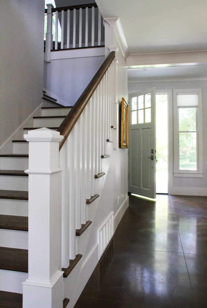 A white staircase with wood steps and a door.