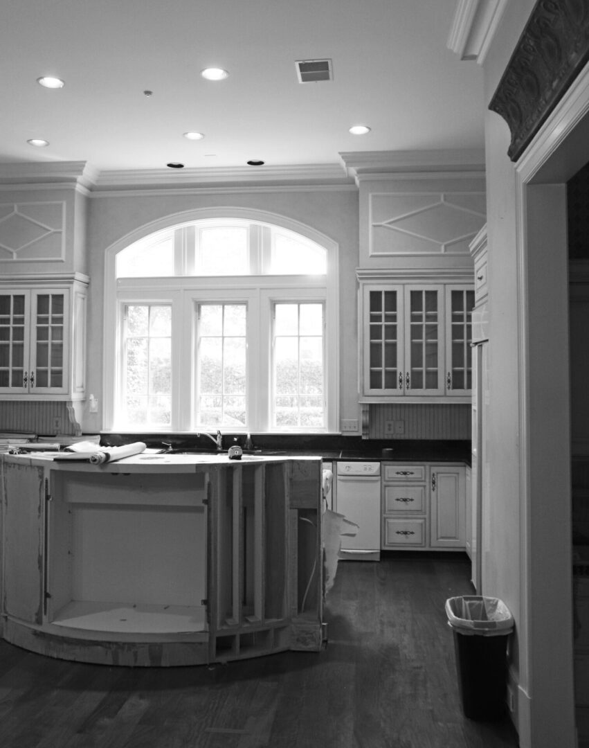 A kitchen with white cabinets and black counter tops.