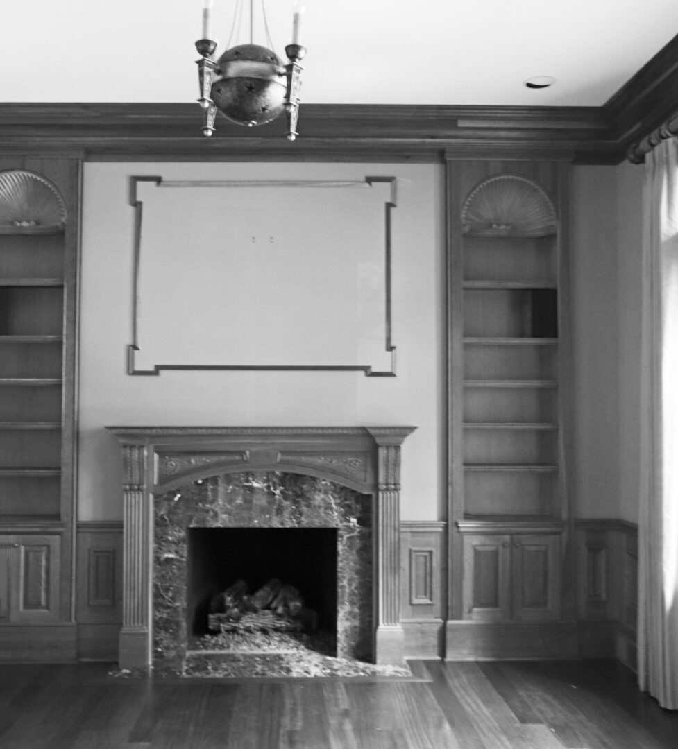 A fireplace in the corner of a room with wooden floors.