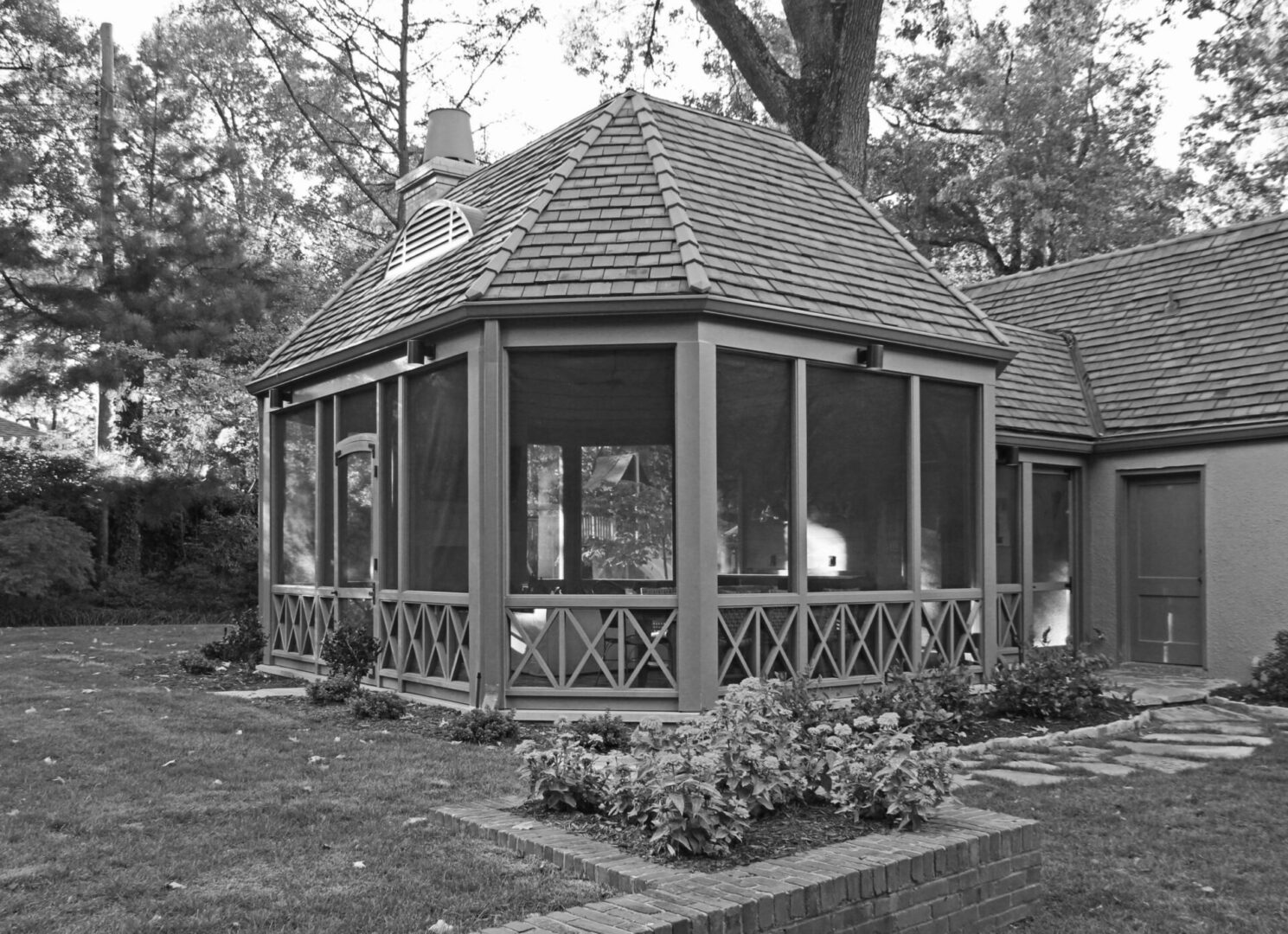 A black and white photo of a gazebo in the middle of a garden.