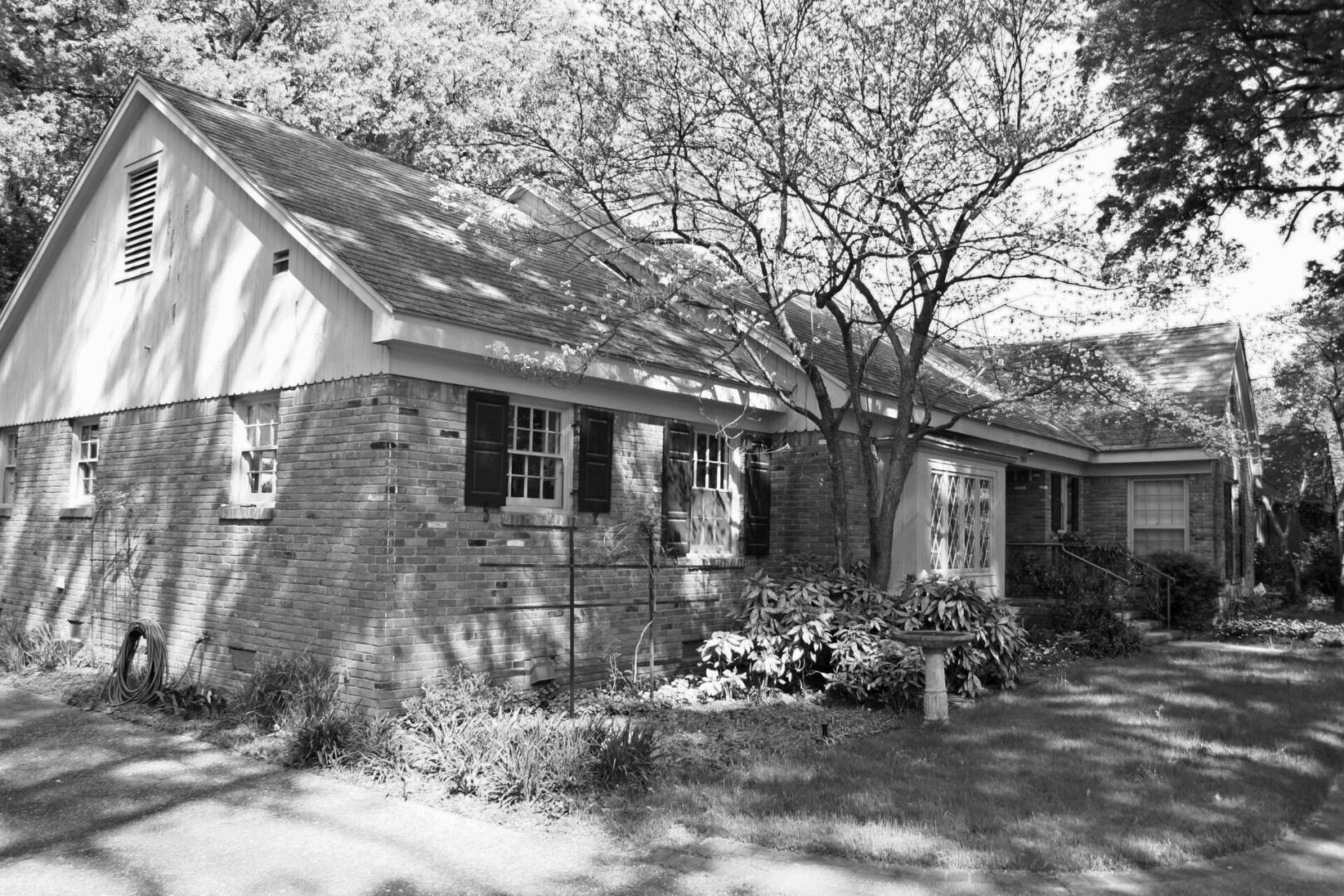 A black and white photo of a house with flowers in front.