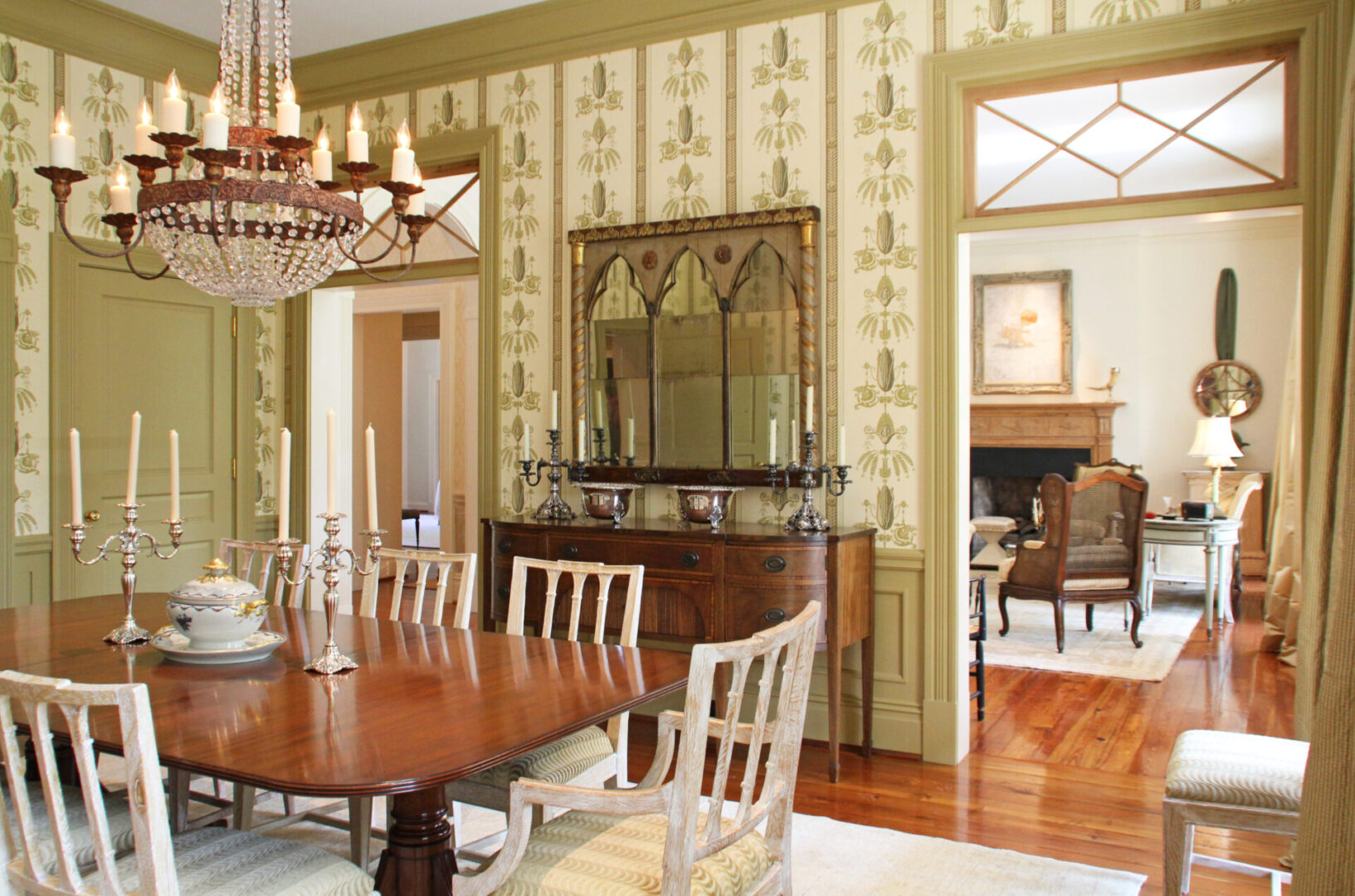 A dining room with a table and chairs, fireplace and wall paper.