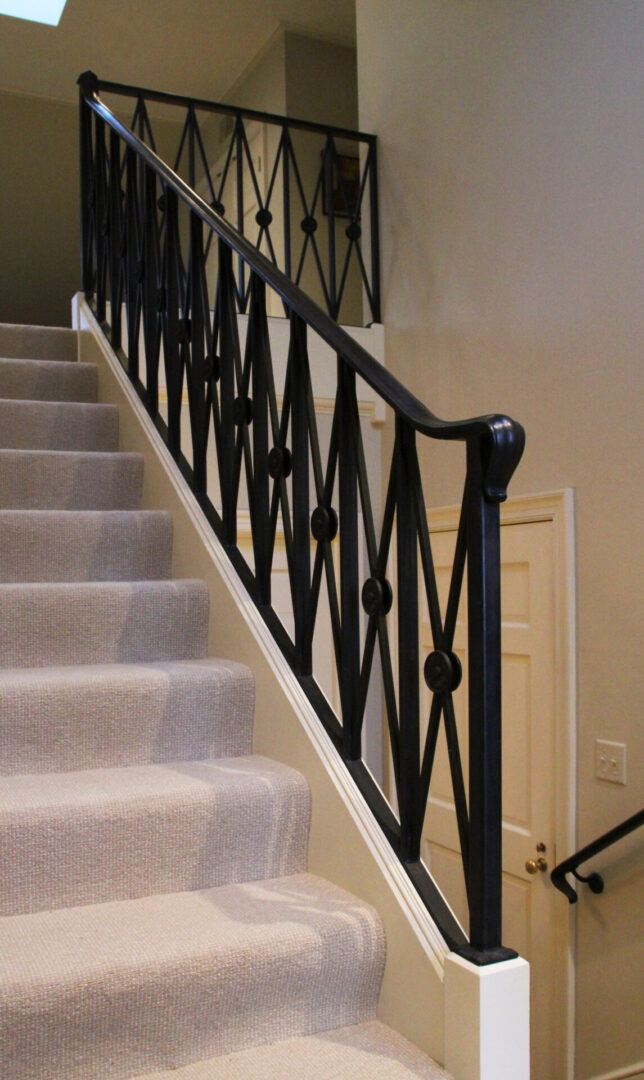 A staircase with white carpeted steps and black railing.