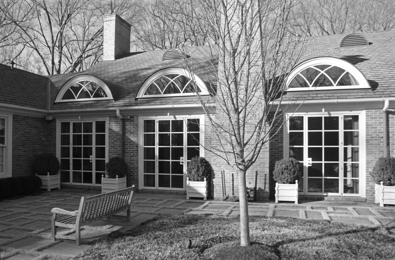 A black and white photo of two houses with benches.