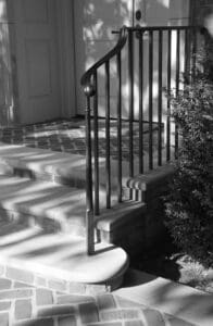 A black and white photo of stairs in front of the door.