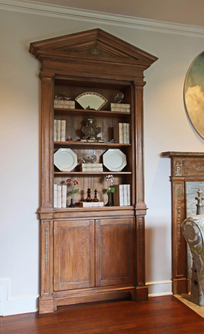 French Provincial wooden cabinet with white plates on top of it.