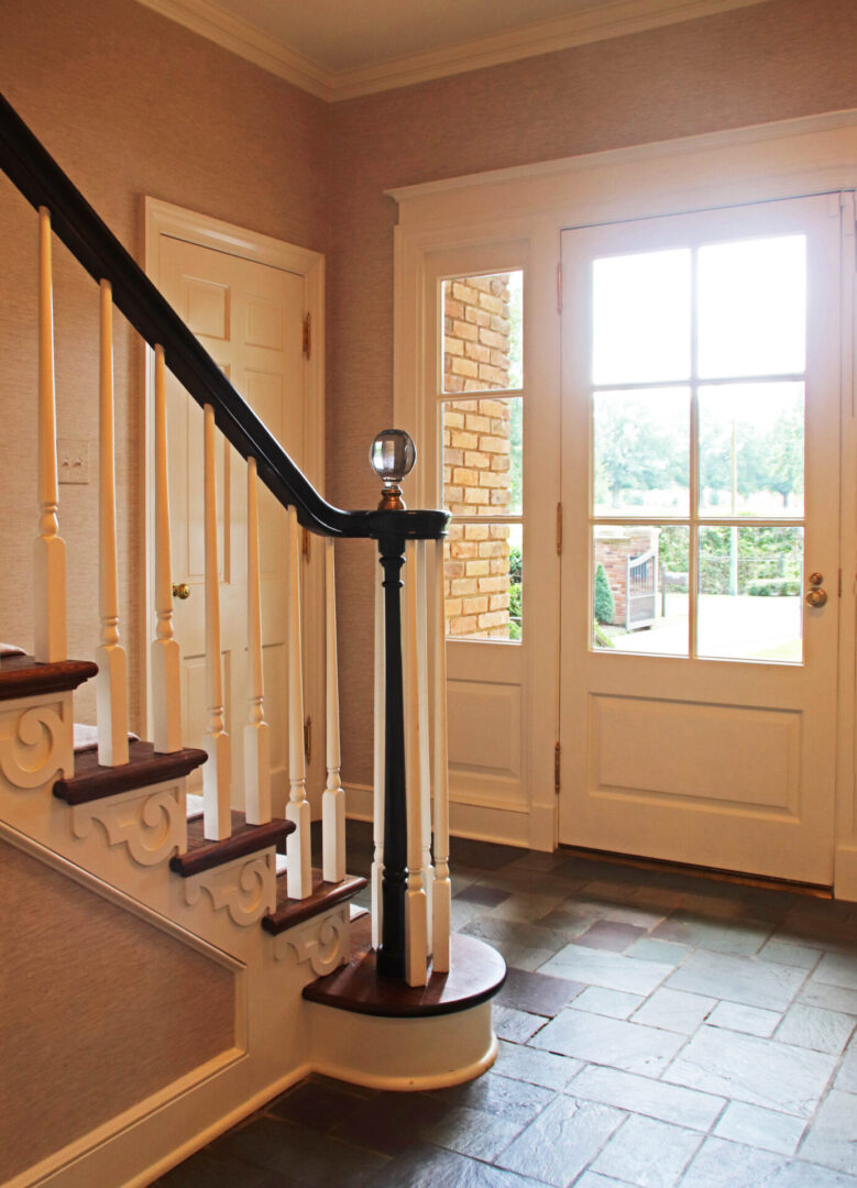 French Provincial view of the front door and stairs in a home.