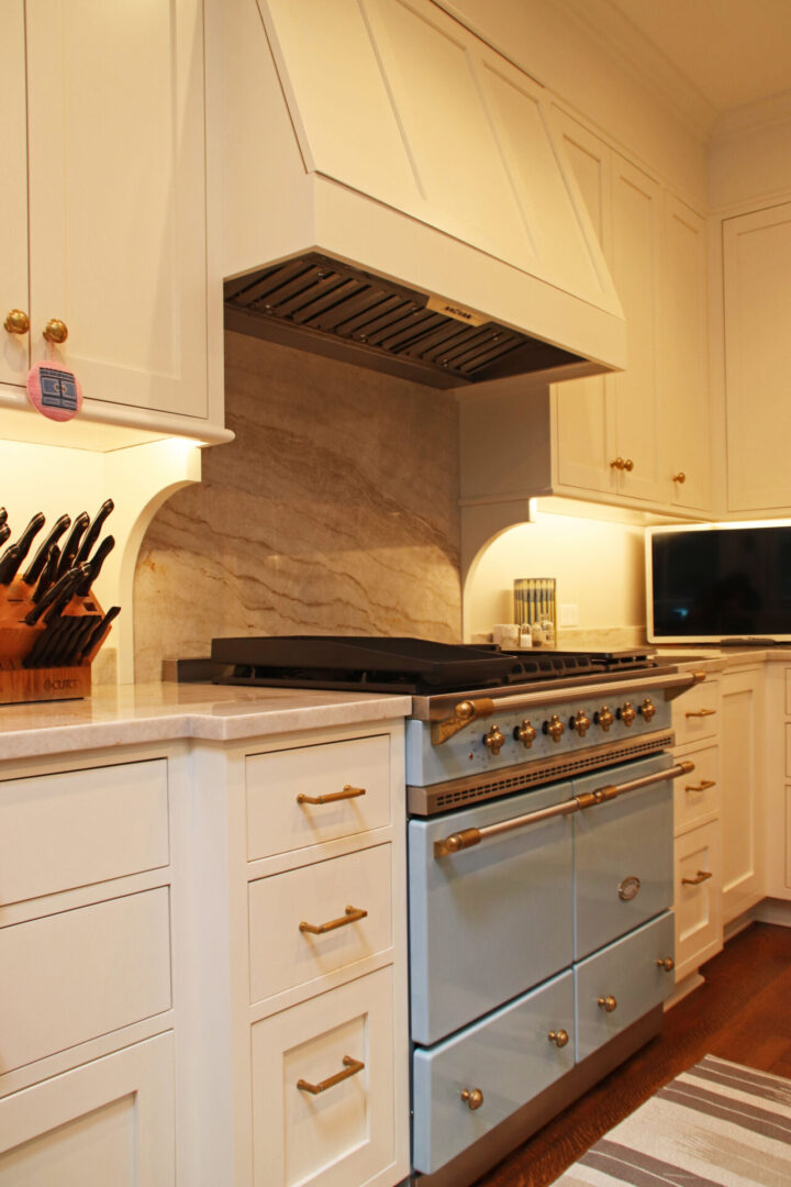 A kitchen with white cabinets and blue oven.