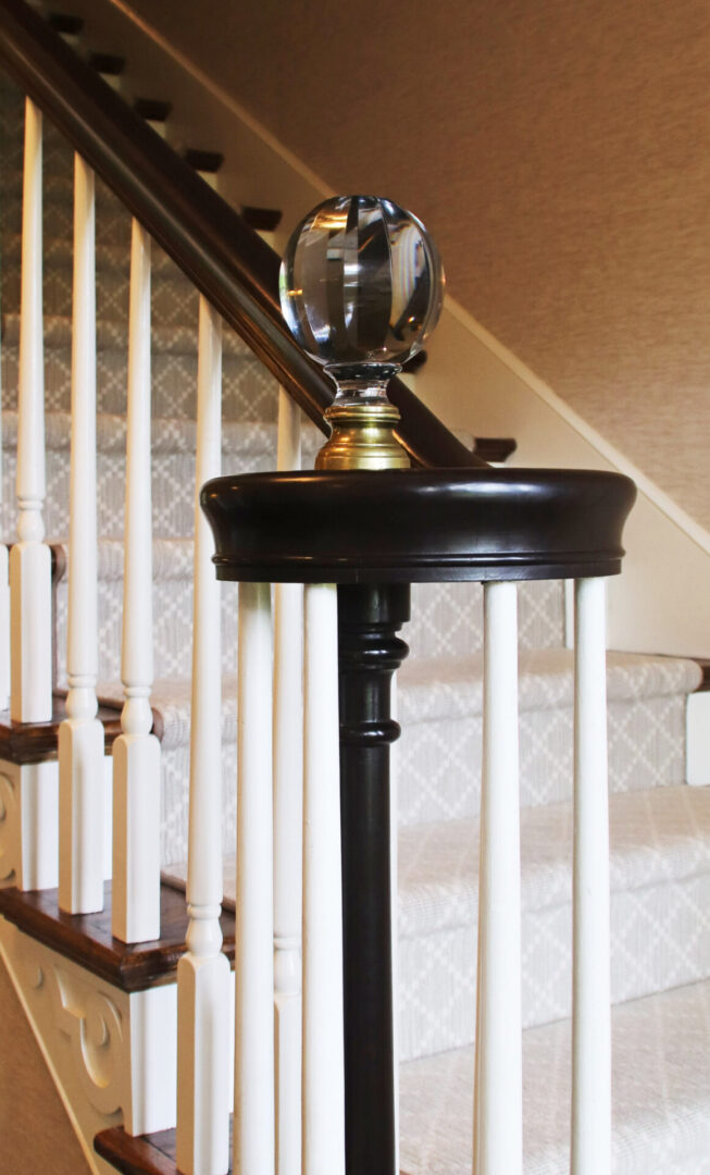 A lamp on top of a wooden stand in front of stairs.