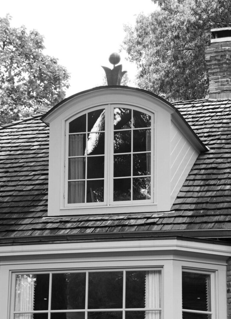 A black and white photo of a window in the roof.