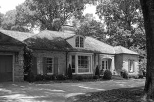 A black and white photo of a house with trees in the background.