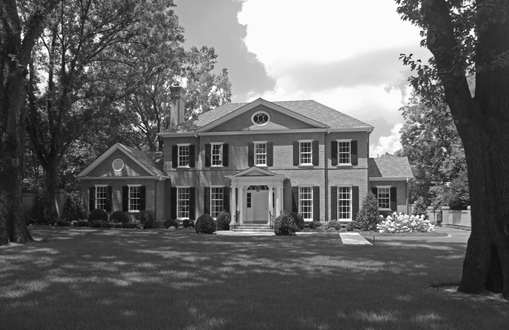 A large brick house with trees in the background.