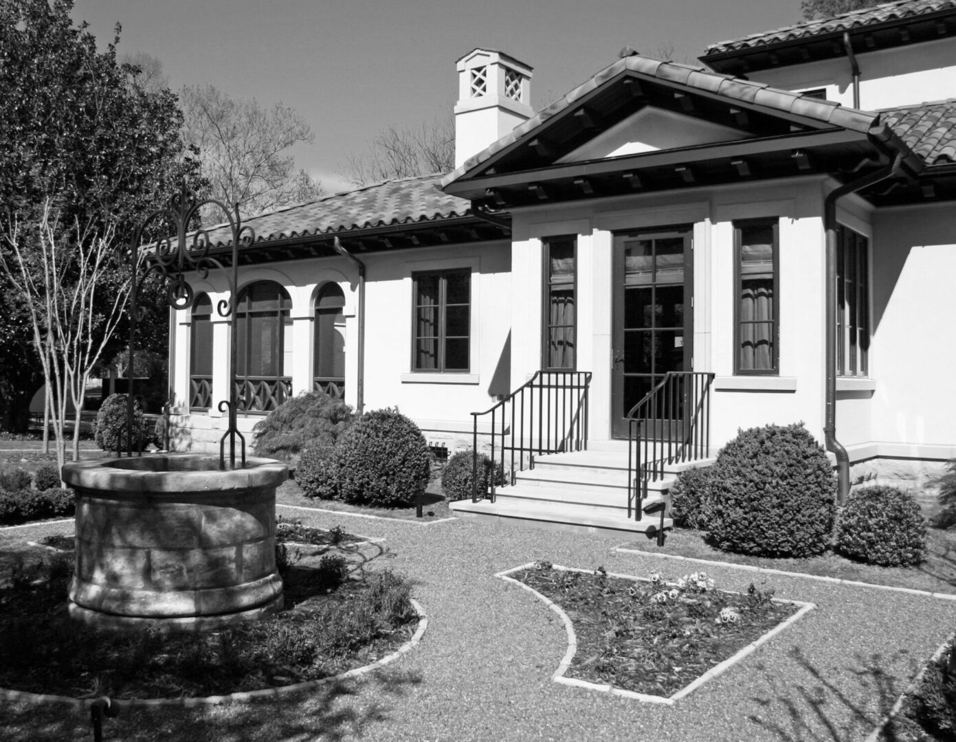 A black and white photo of a house with a fountain.