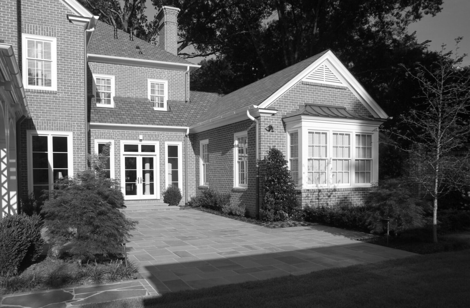 A black and white photo of a house with a driveway.