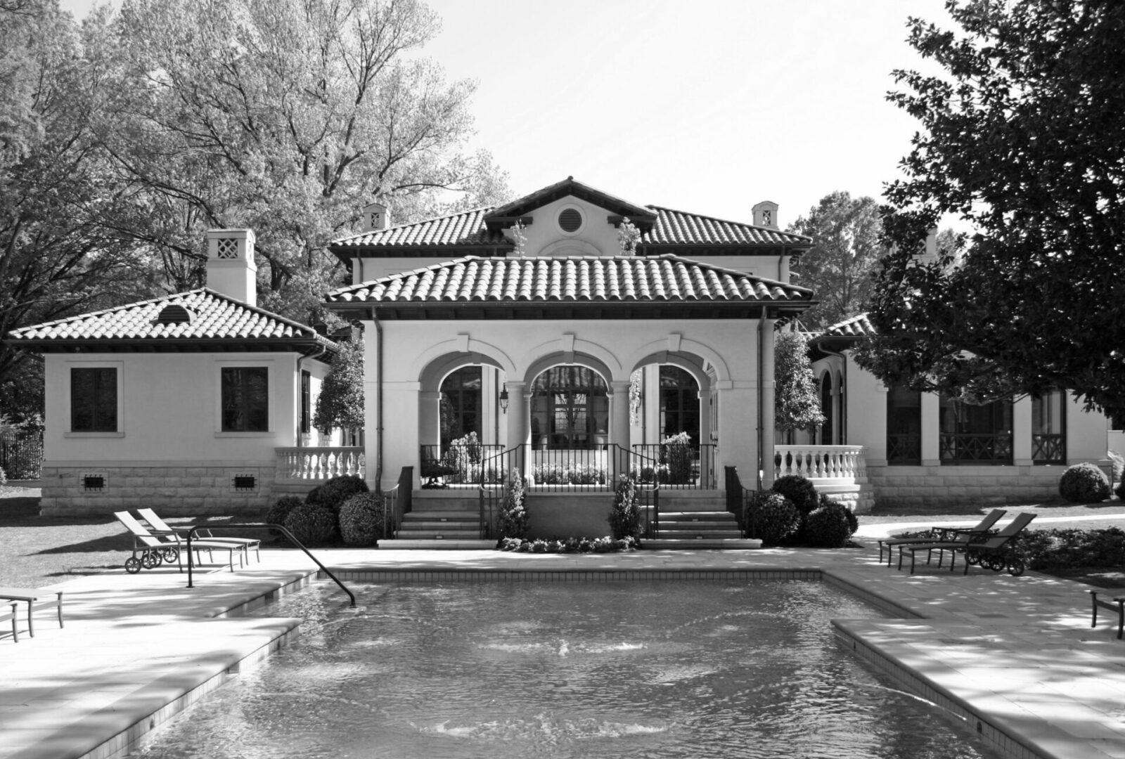 A black and white photo of a house with a pool.