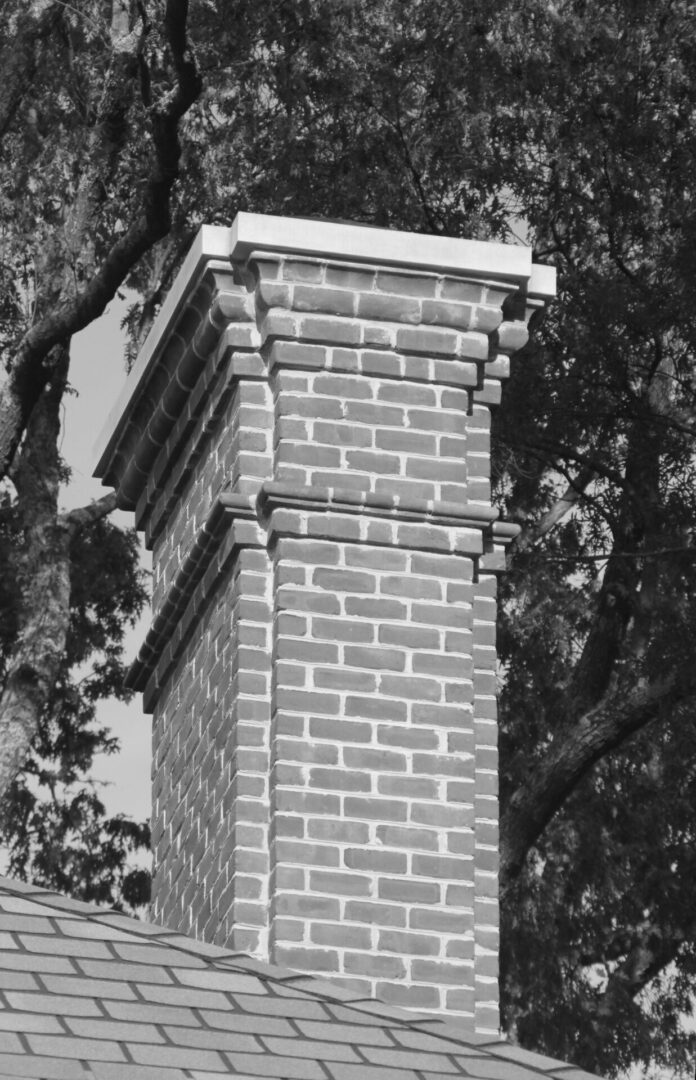 A brick chimney with a tree in the background.