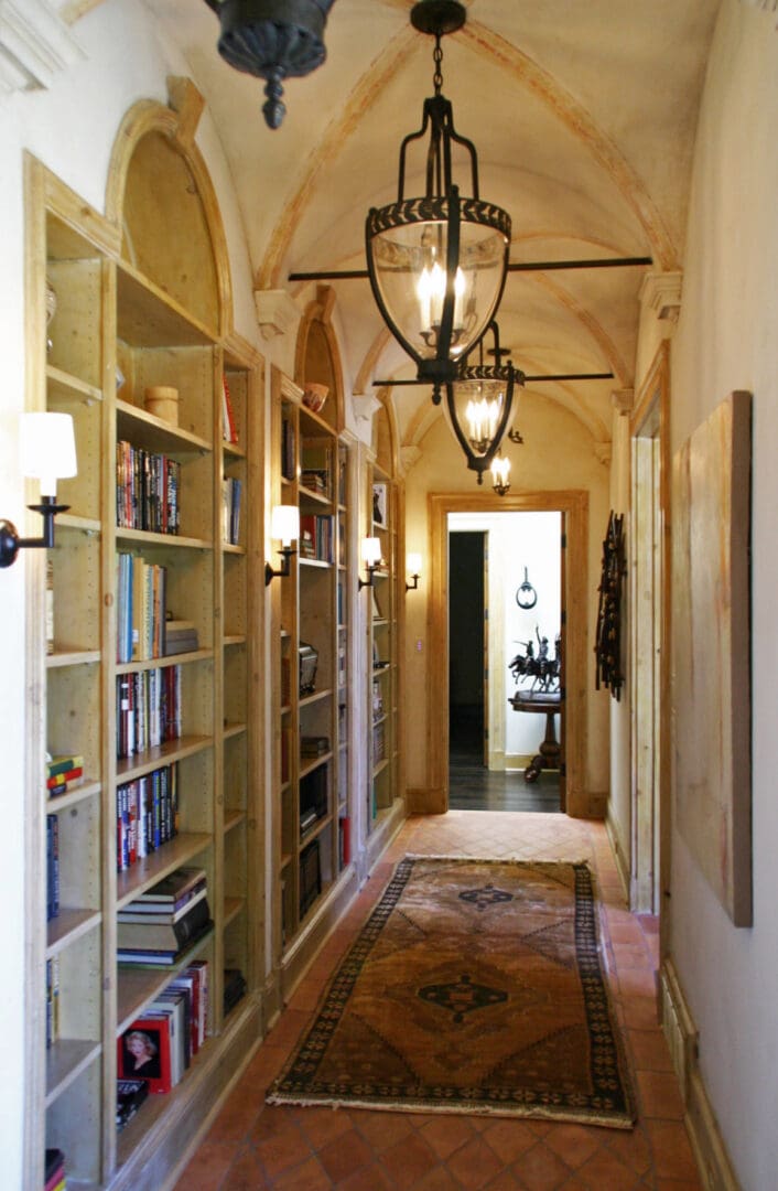 A hallway with bookcases and lamps in it