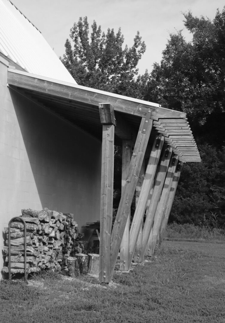 A black and white photo of a building with wood piled up.