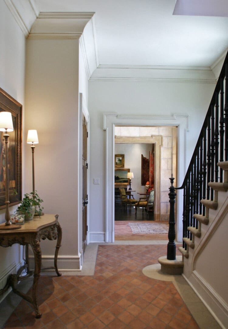 A hallway with stairs and a table in the middle.