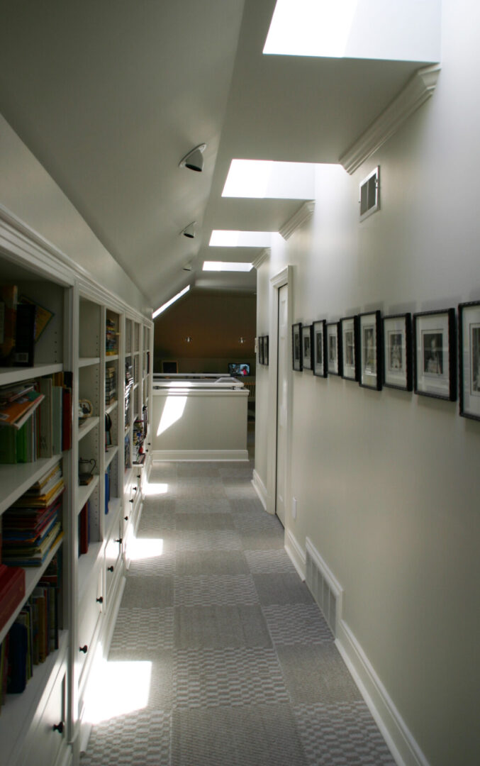 A hallway with bookcases and pictures on the wall.