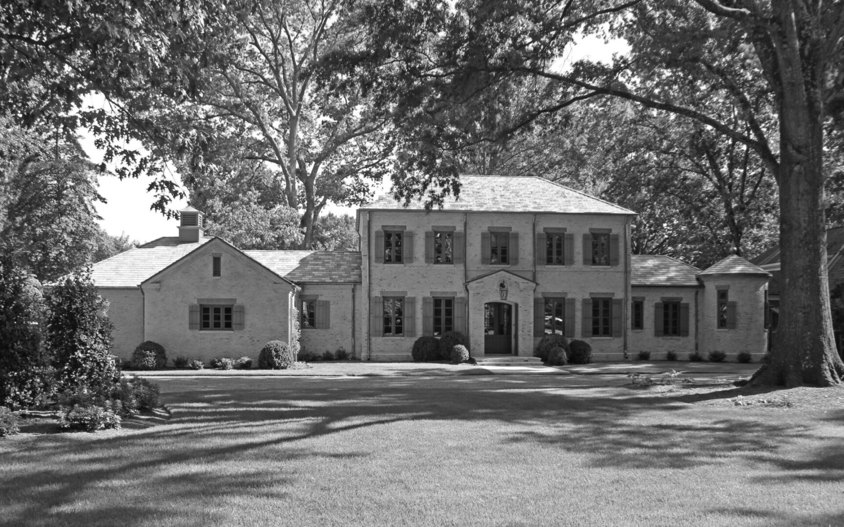 A large white house with trees in the background.