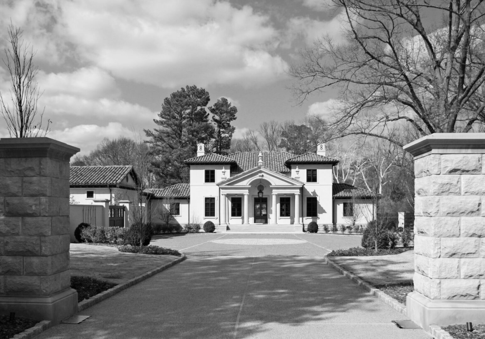 A black and white photo of a house with trees in the background.