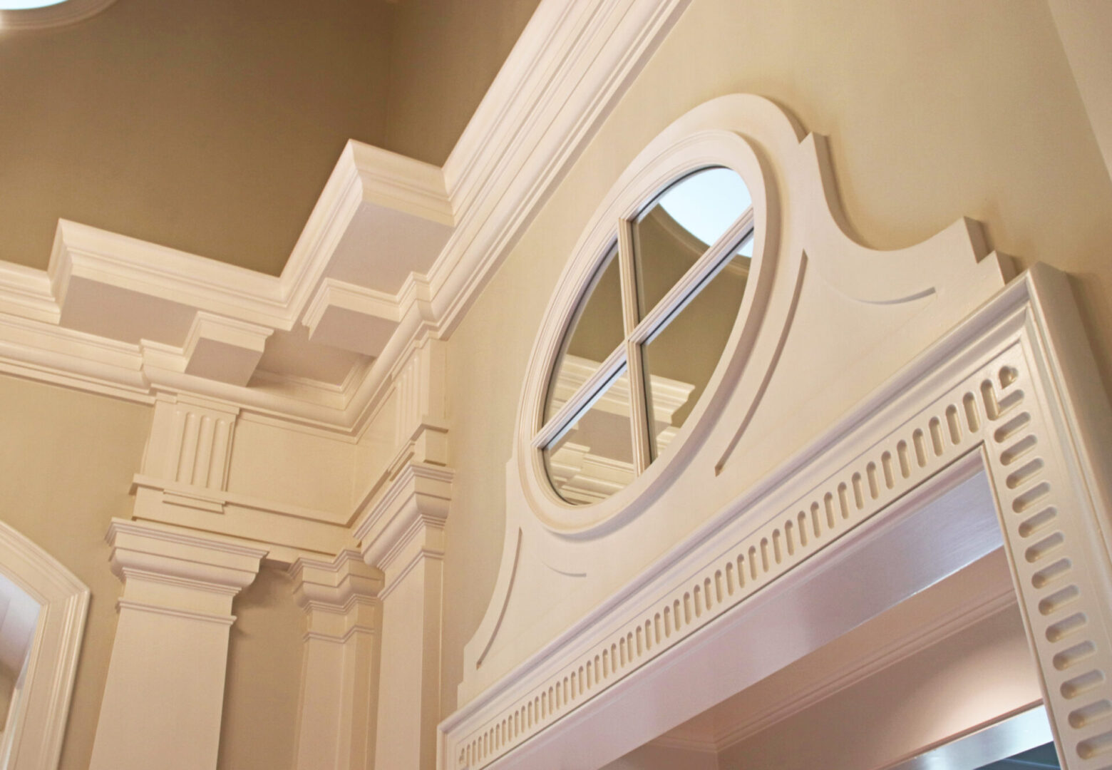 A white wall with a round window and a decorative trim.