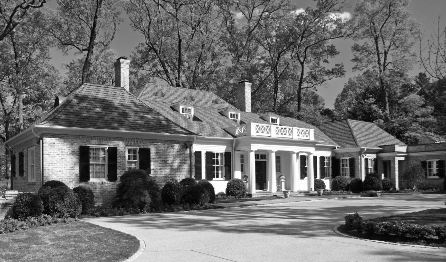 A black and white photo of a house with trees in the background.