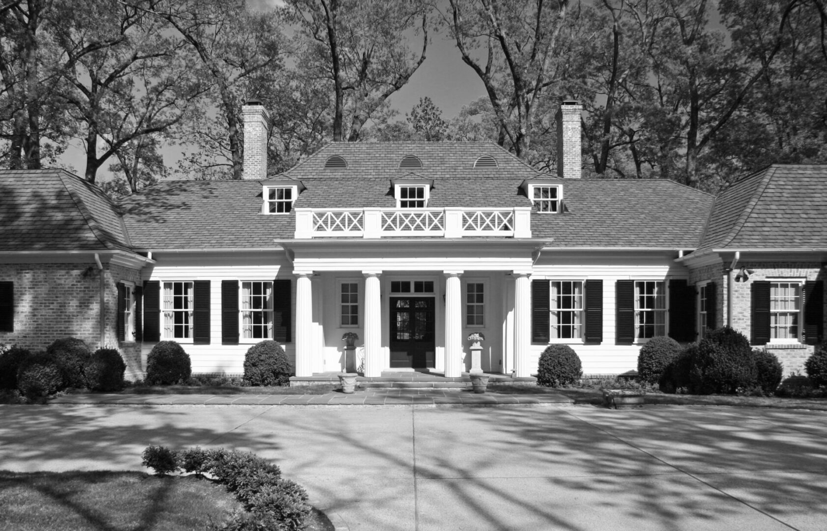 A black and white photo of a house with trees in the background.