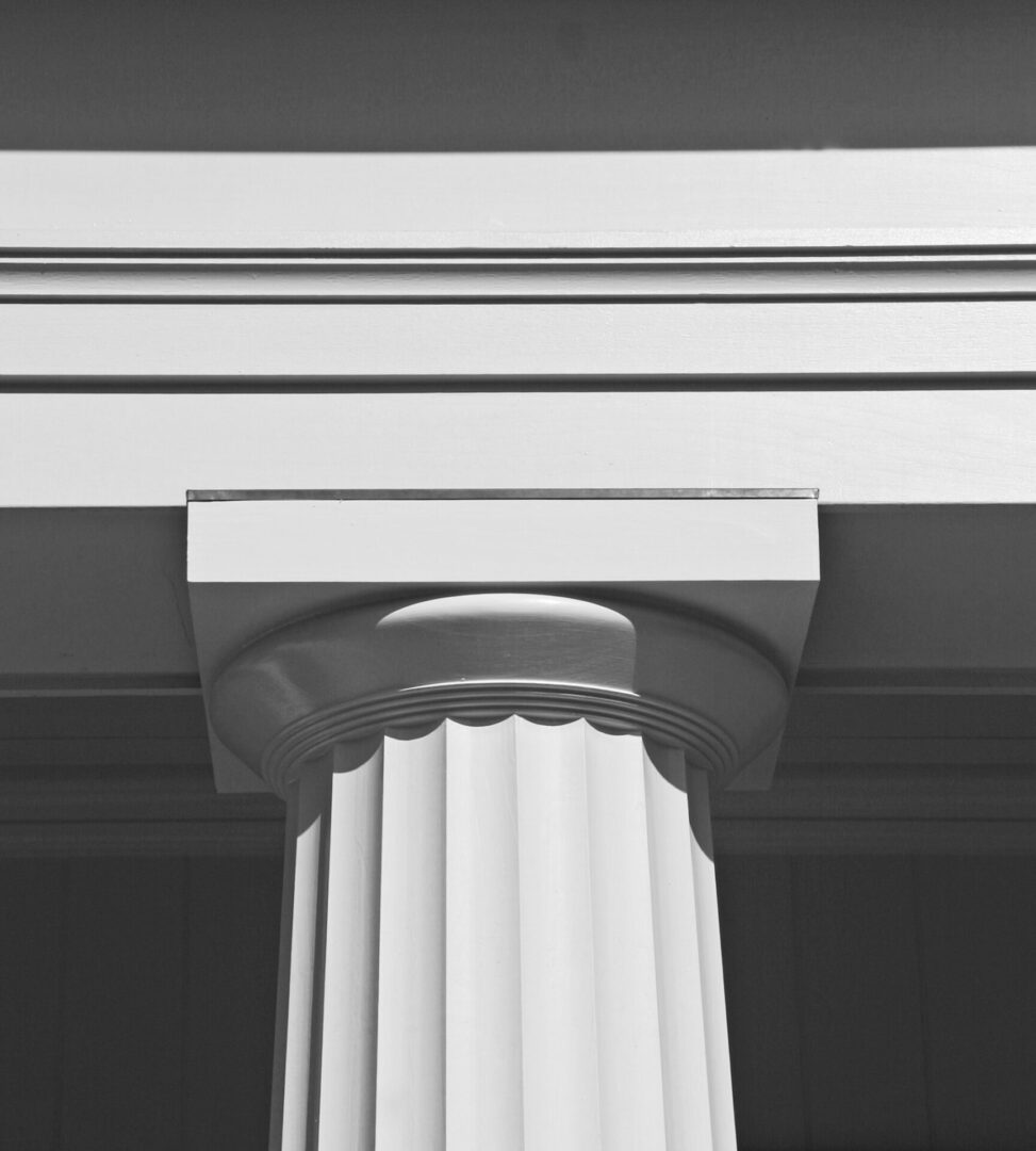 A white pillar with a capital on top of it.