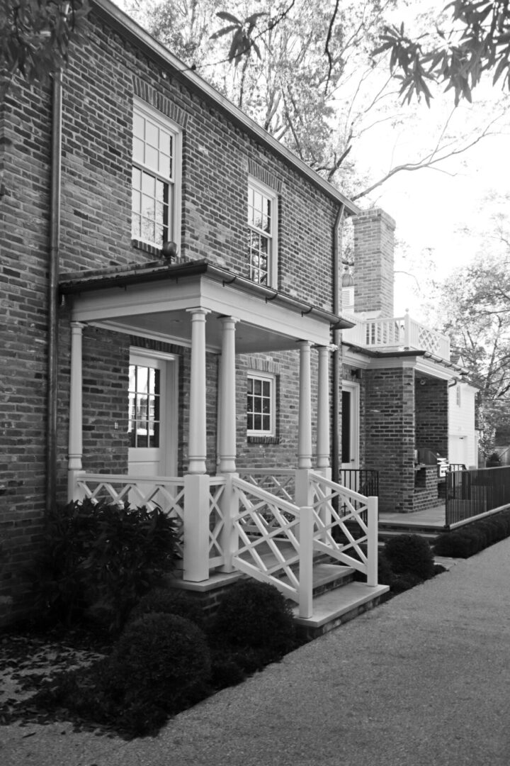 A black and white photo of a American Georgian with a porch.