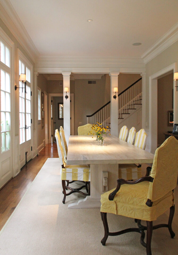 A dining room with yellow chairs and white table.