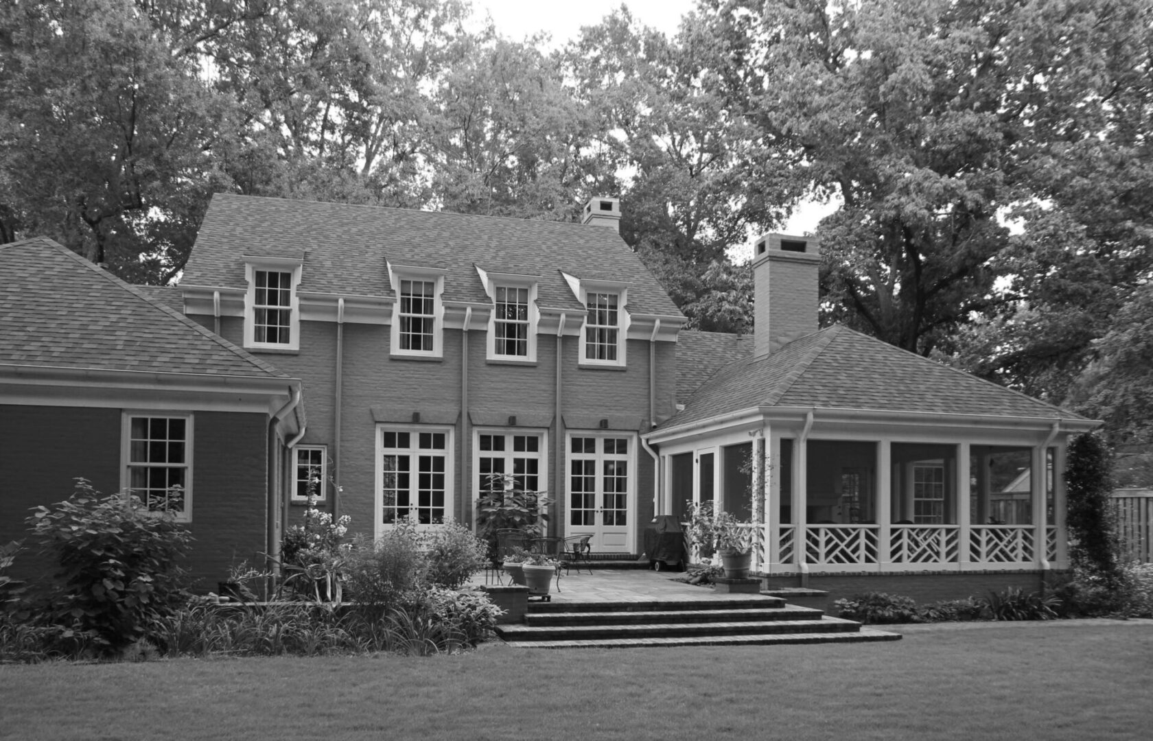 A black and white photo of a house with a porch.