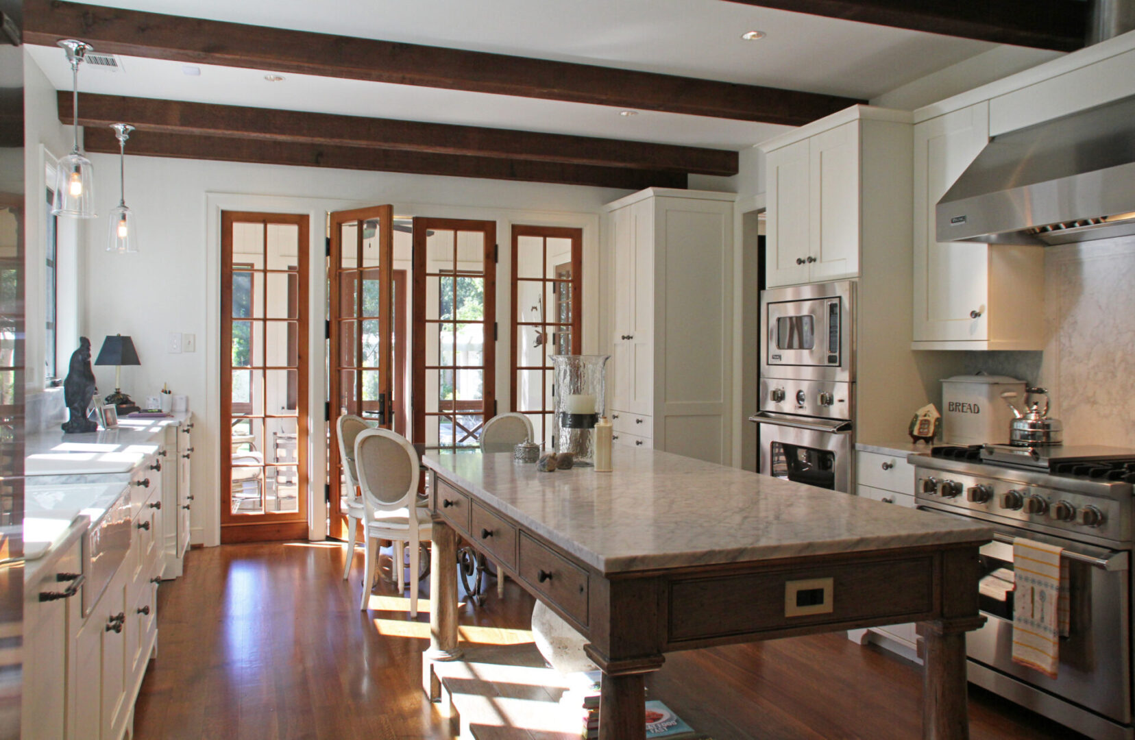 A kitchen with white cabinets and wood floors.