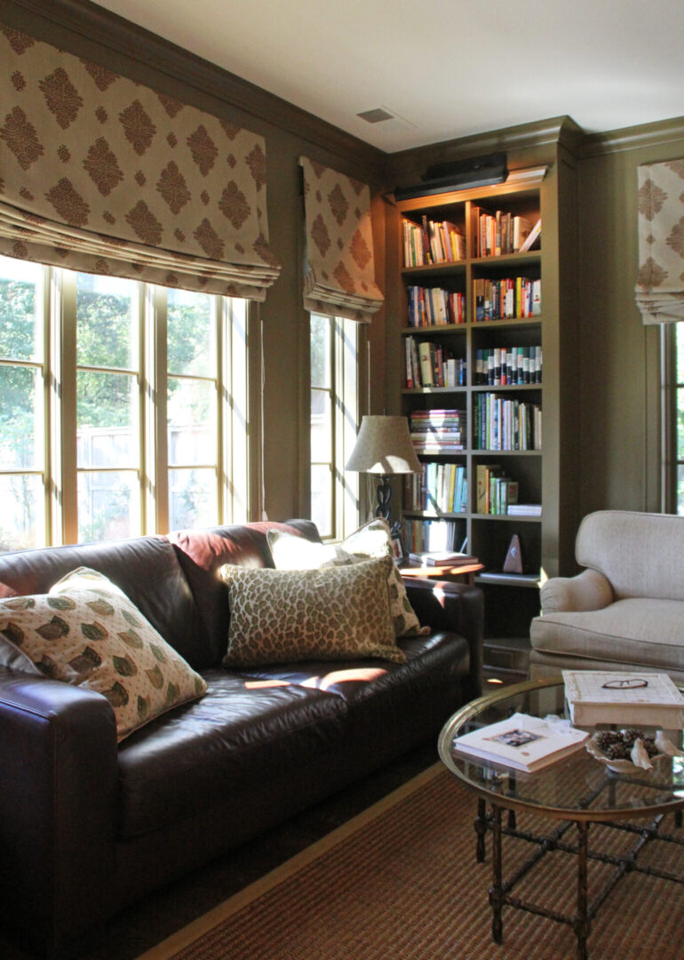 A living room with brown leather furniture and books.