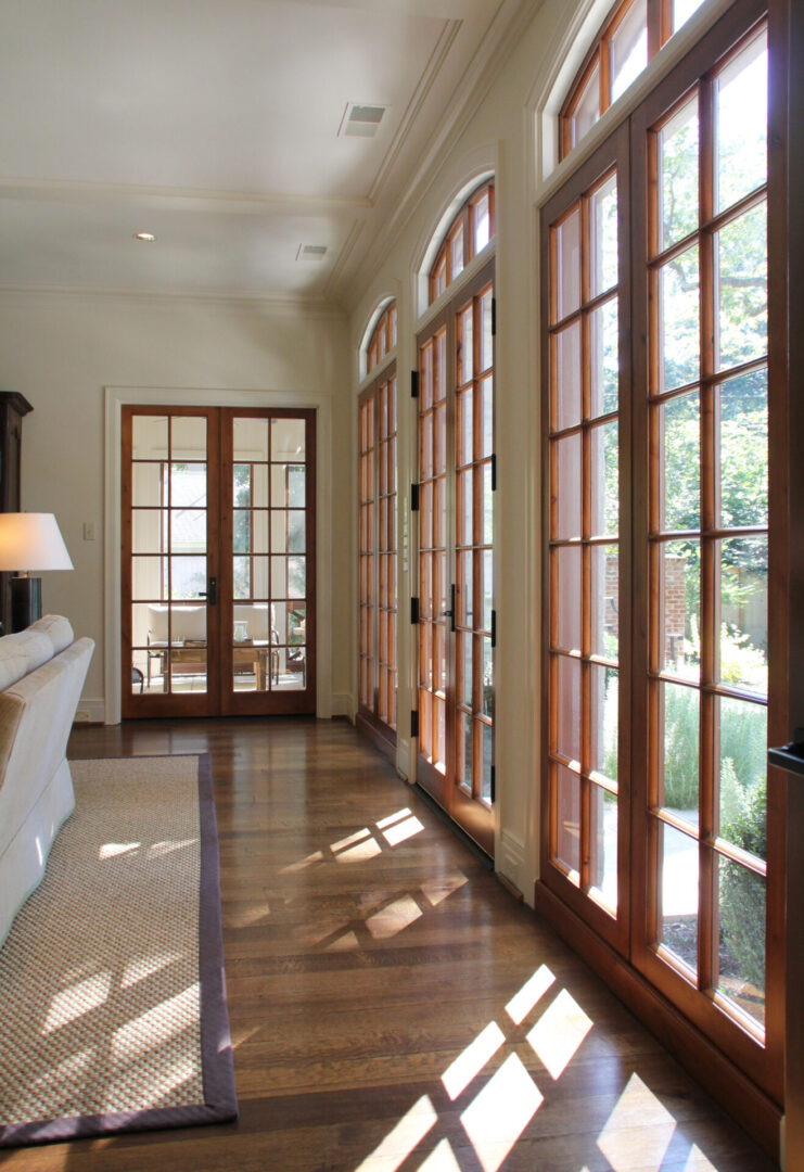 A long hallway with two large windows and a couch.