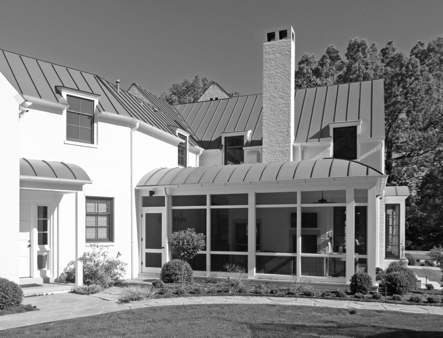 A black and white photo of a house with a porch.