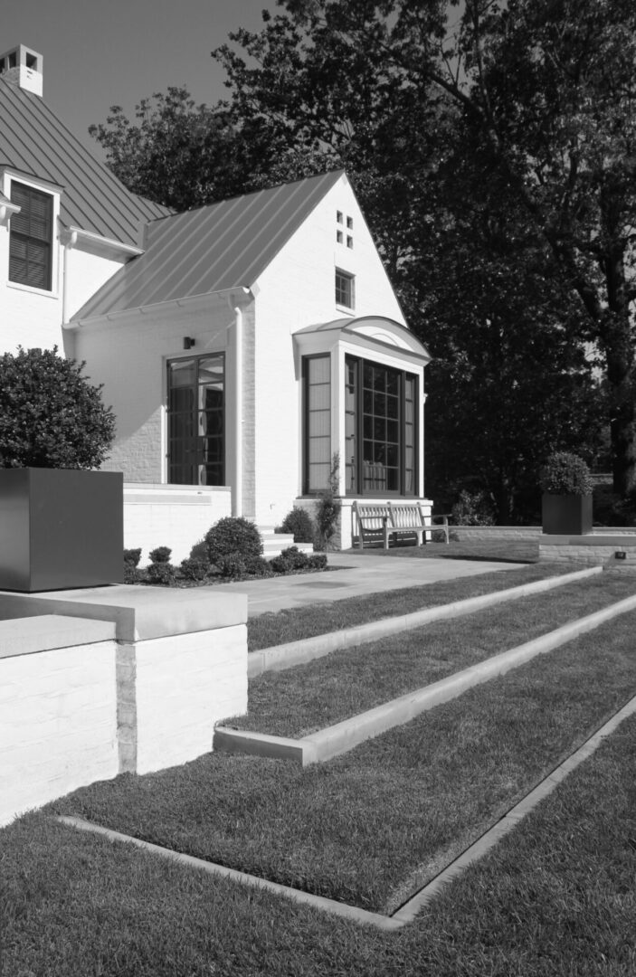 A black and white photo of a house with steps leading to the front door.