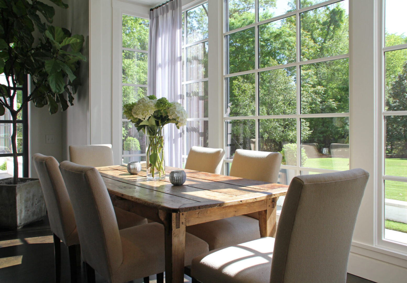 A dining room table with chairs and a vase of flowers.