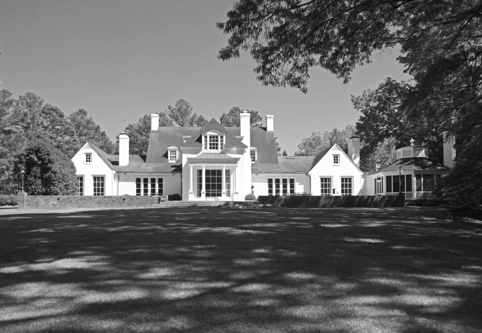 A large white house with trees in the background.